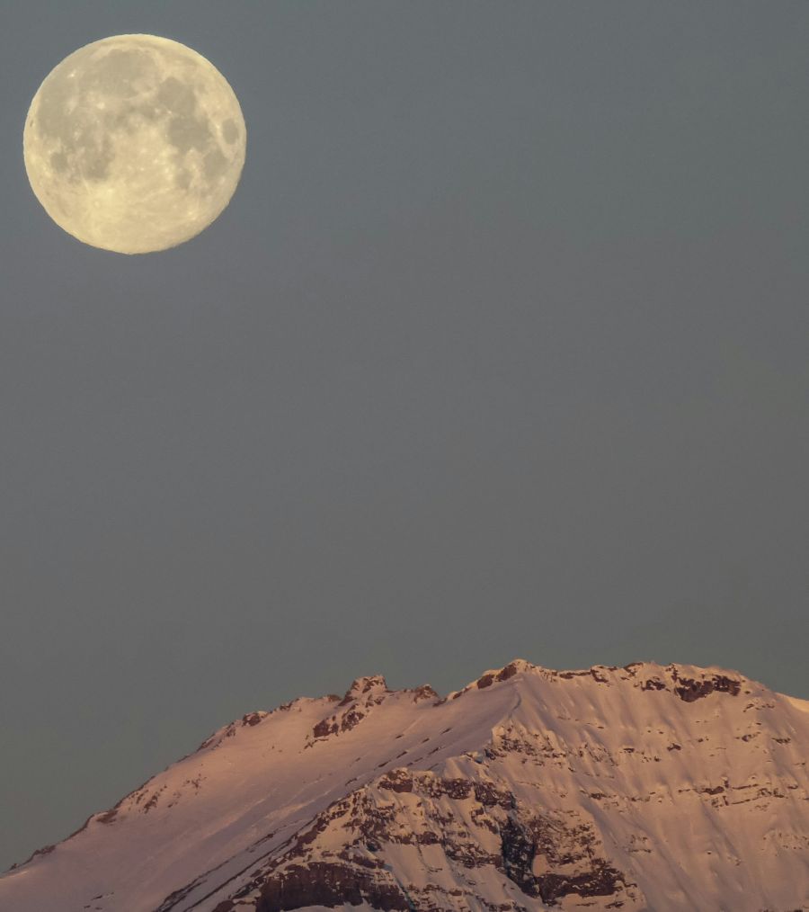 <who>Photo credit: Kym MacKinnon on Unsplash</who>February's full moon above a snowy mountain top.